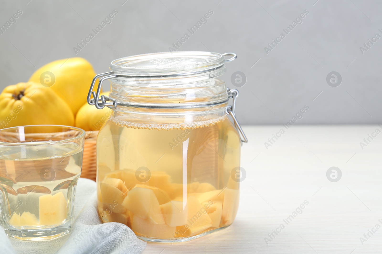 Photo of Delicious quince drink and fresh fruits on white wooden table, space for text