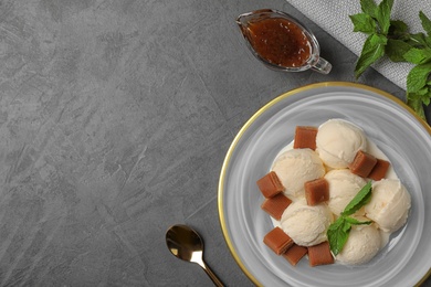 Flat lay composition of ice cream with caramel candies and space for text on grey table
