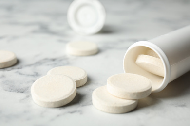 Photo of Bottle with vitamin pills on white marble table, closeup