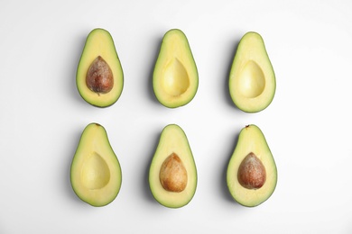 Cut fresh ripe avocados on white background, top view