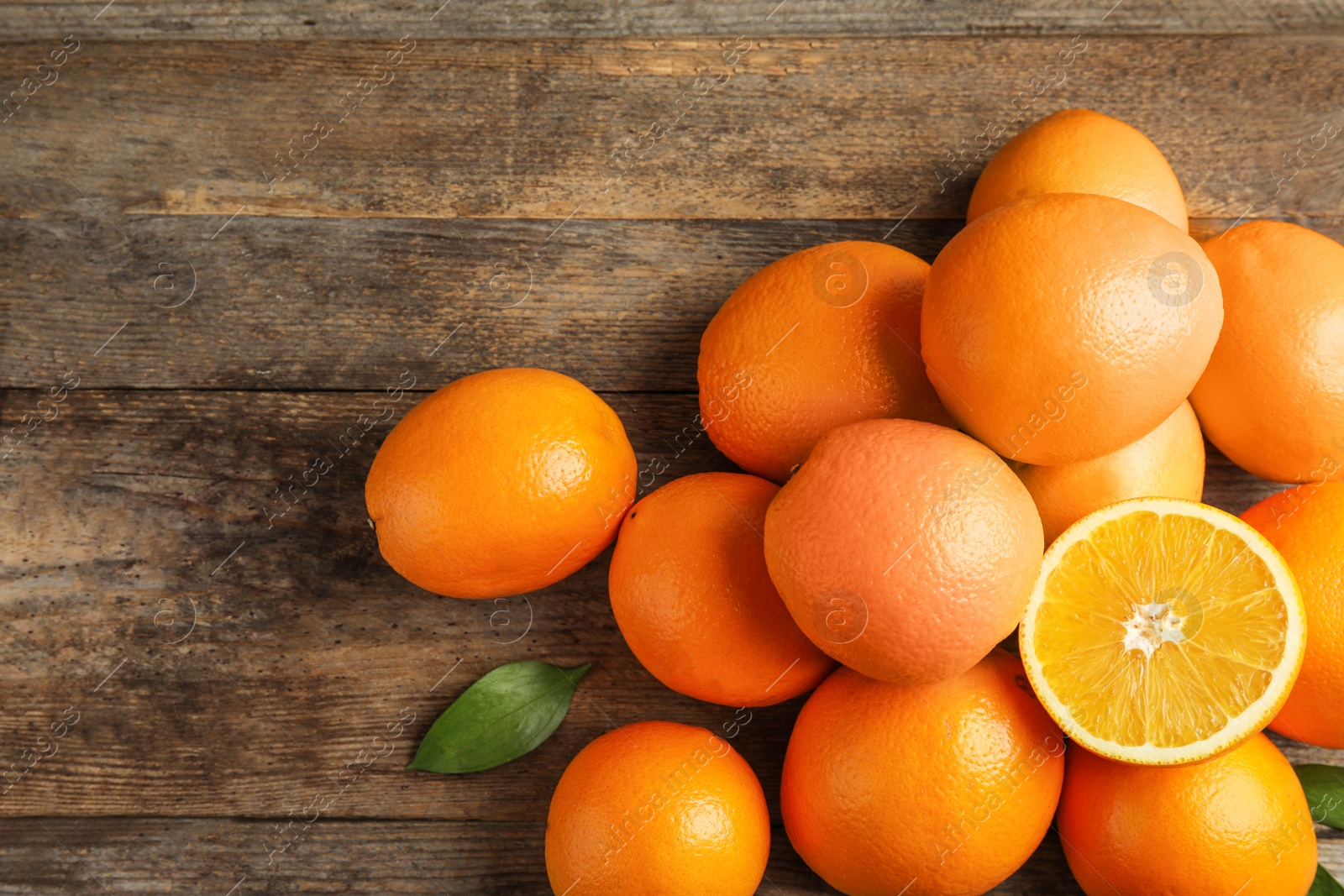 Photo of Heap of fresh oranges on wooden table, top view with space for text