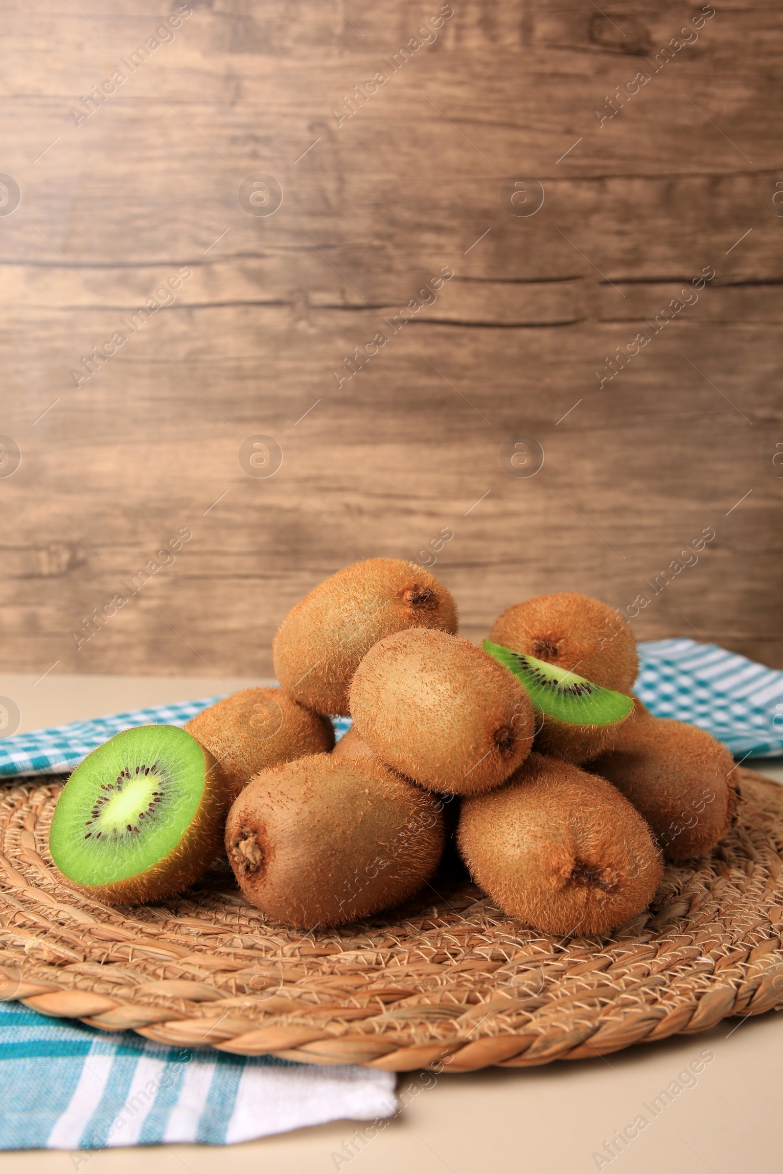 Photo of Heap of whole and cut fresh kiwis on white table, space for text