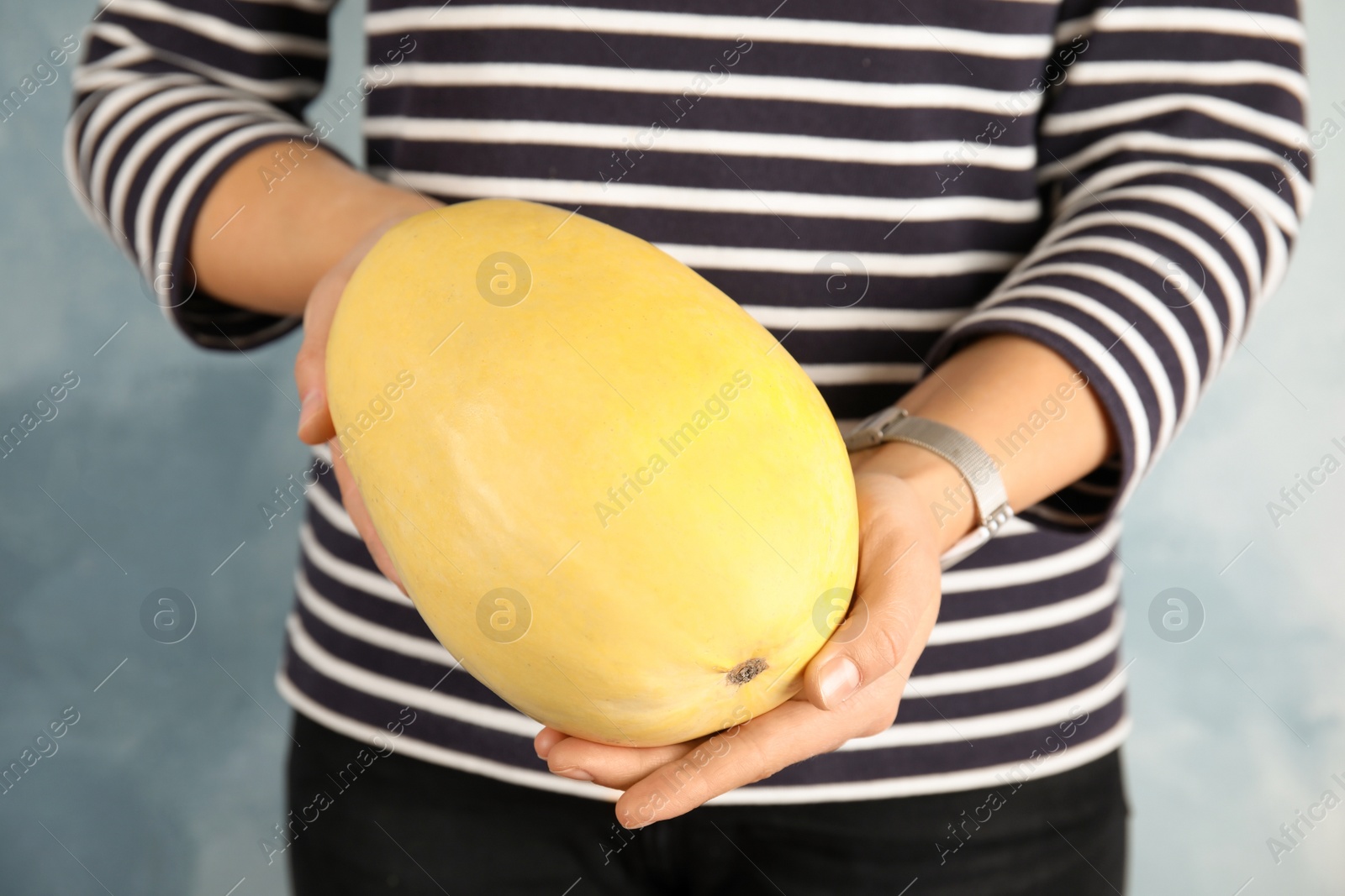 Photo of Woman holding spaghetti squash against color background, closeup