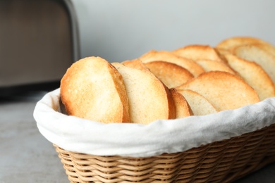 Slices of toasted bread in basket on grey table