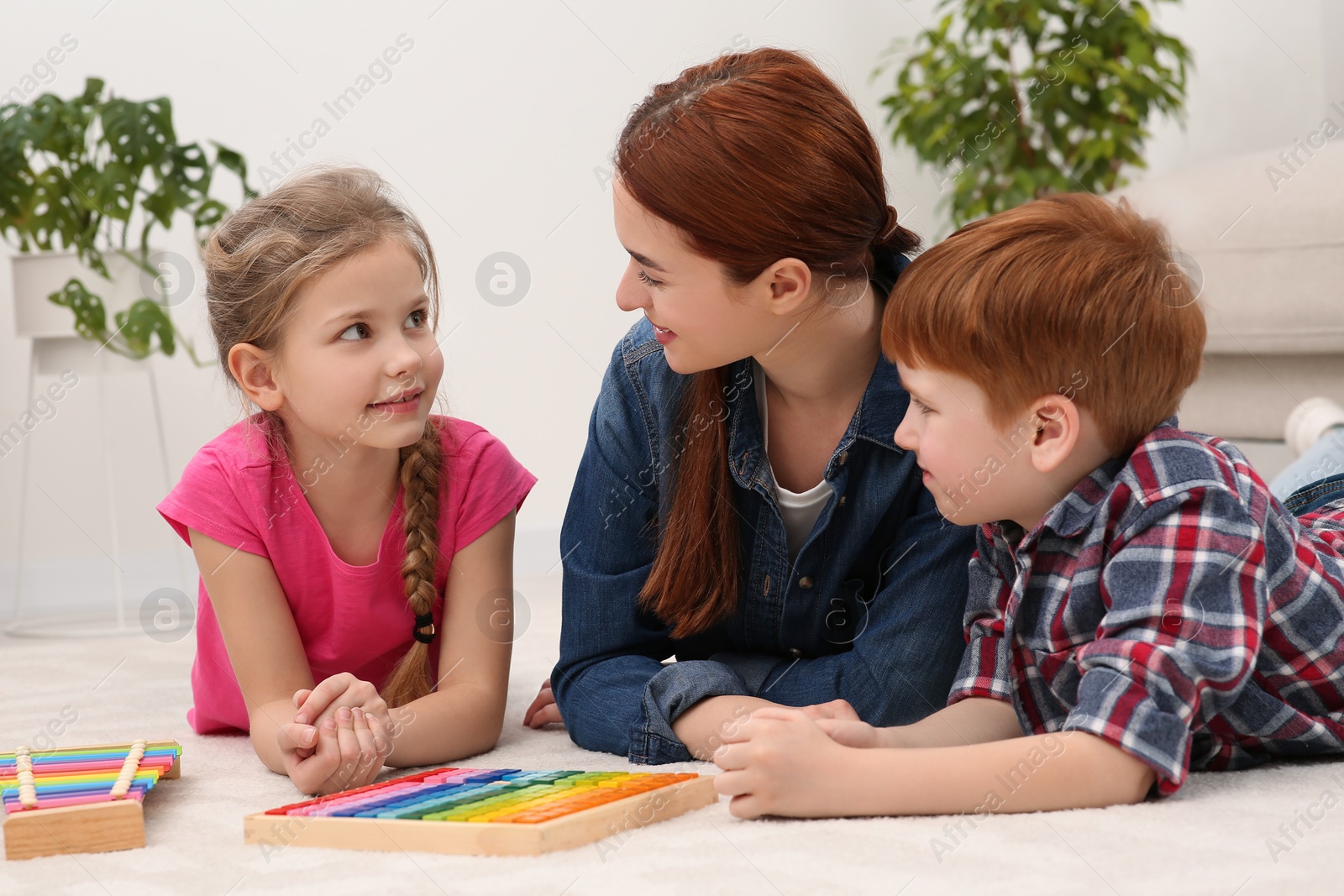 Photo of Happy mother and children playing with different math game kits on floor in room. Study mathematics with pleasure