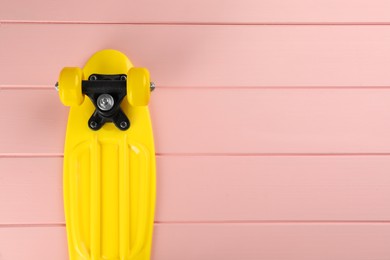 Photo of Yellow skateboard on pink wooden background, top view. Space for text