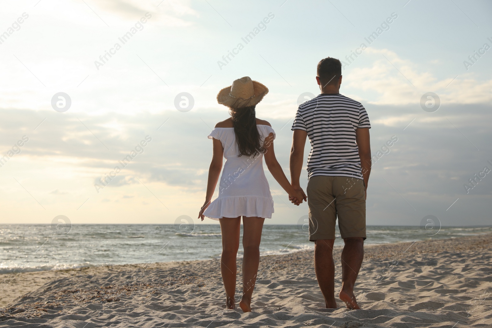 Photo of Lovely couple spending time together on beach, back view