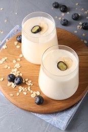 Photo of Tasty yogurt in glasses, oats and blueberries on grey table