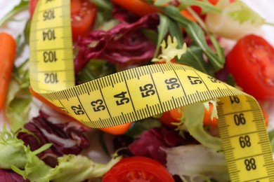 Photo of Healthy salad with measuring tape as background. Diet concept