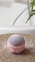 Beautiful bath bomb on wicker mat in bathroom