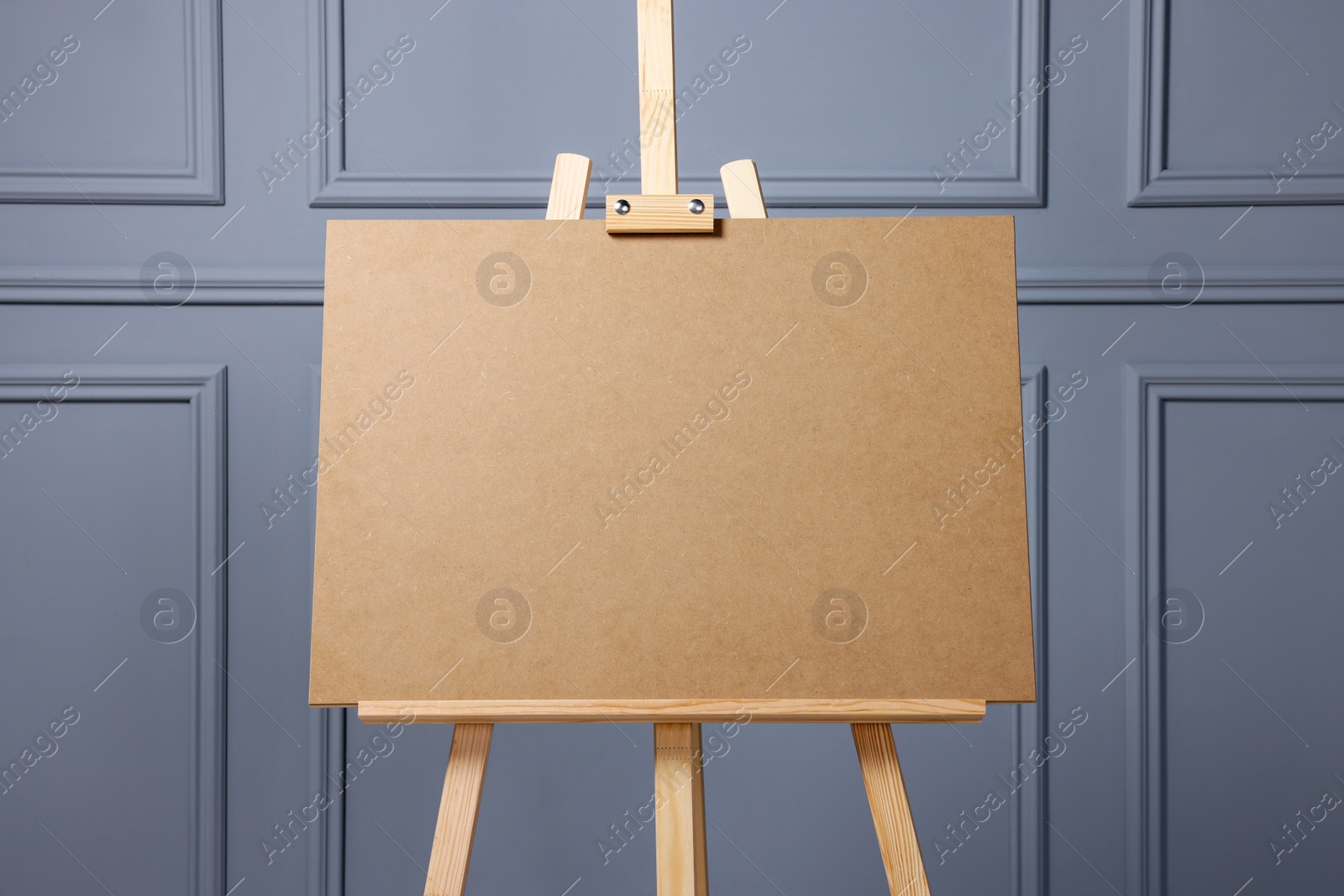Photo of Wooden easel with blank board near grey wall indoors, closeup