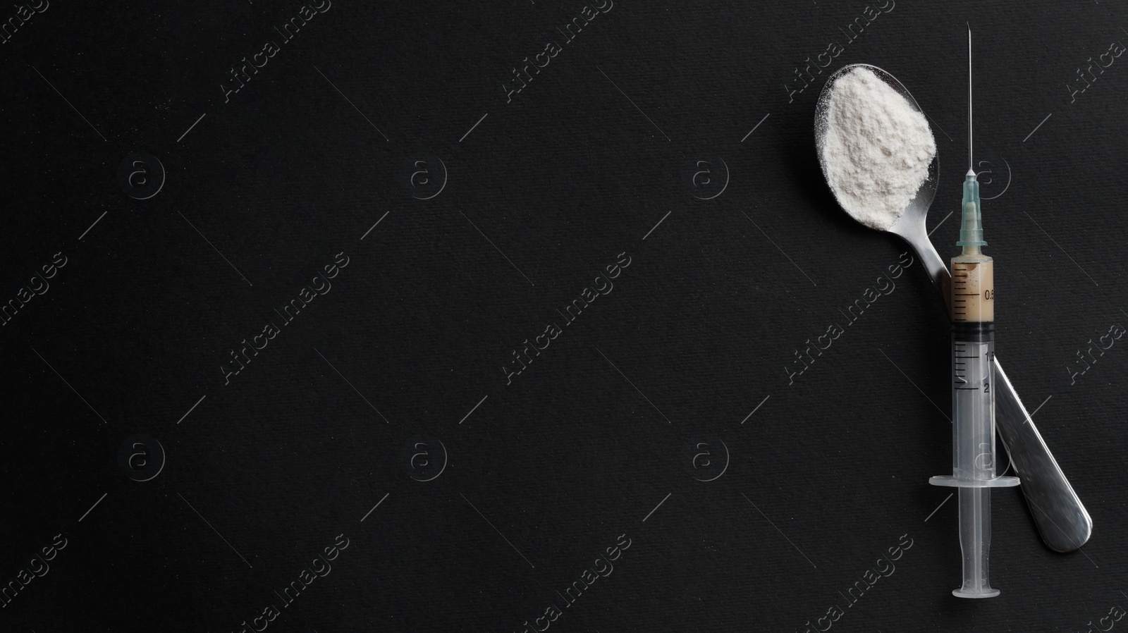 Photo of Spoon with powder, syringe on black background, flat lay and space for text. Hard drugs