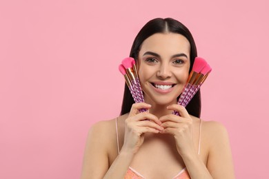 Photo of Happy woman with different makeup brushes on pink background. Space for text