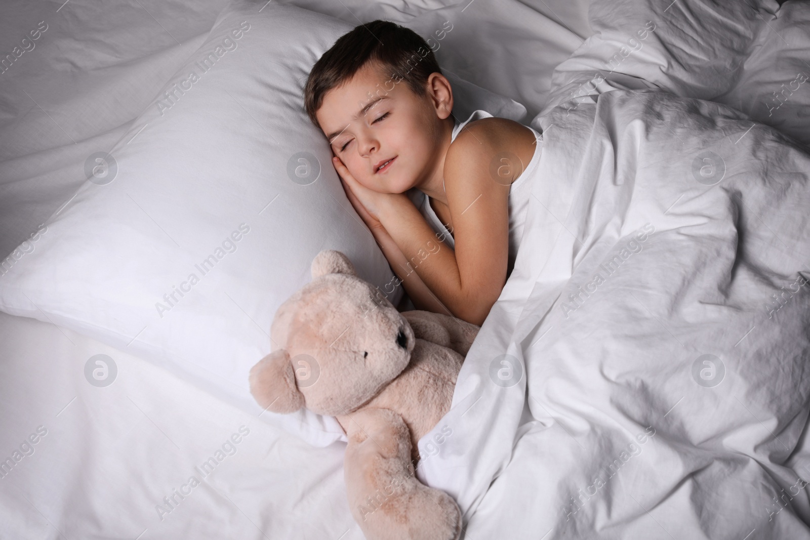 Photo of Little boy sleeping with teddy bear at home. Bedtime