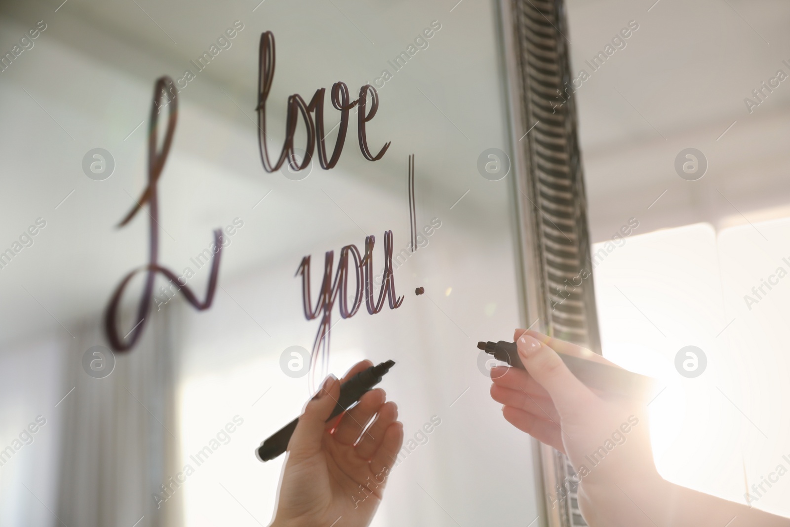 Photo of Woman writing romantic message I Love You on mirror in room, closeup