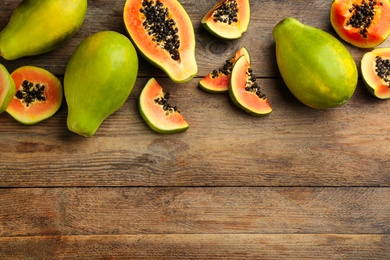 Fresh ripe papaya fruits on wooden table, flat lay. Space for text