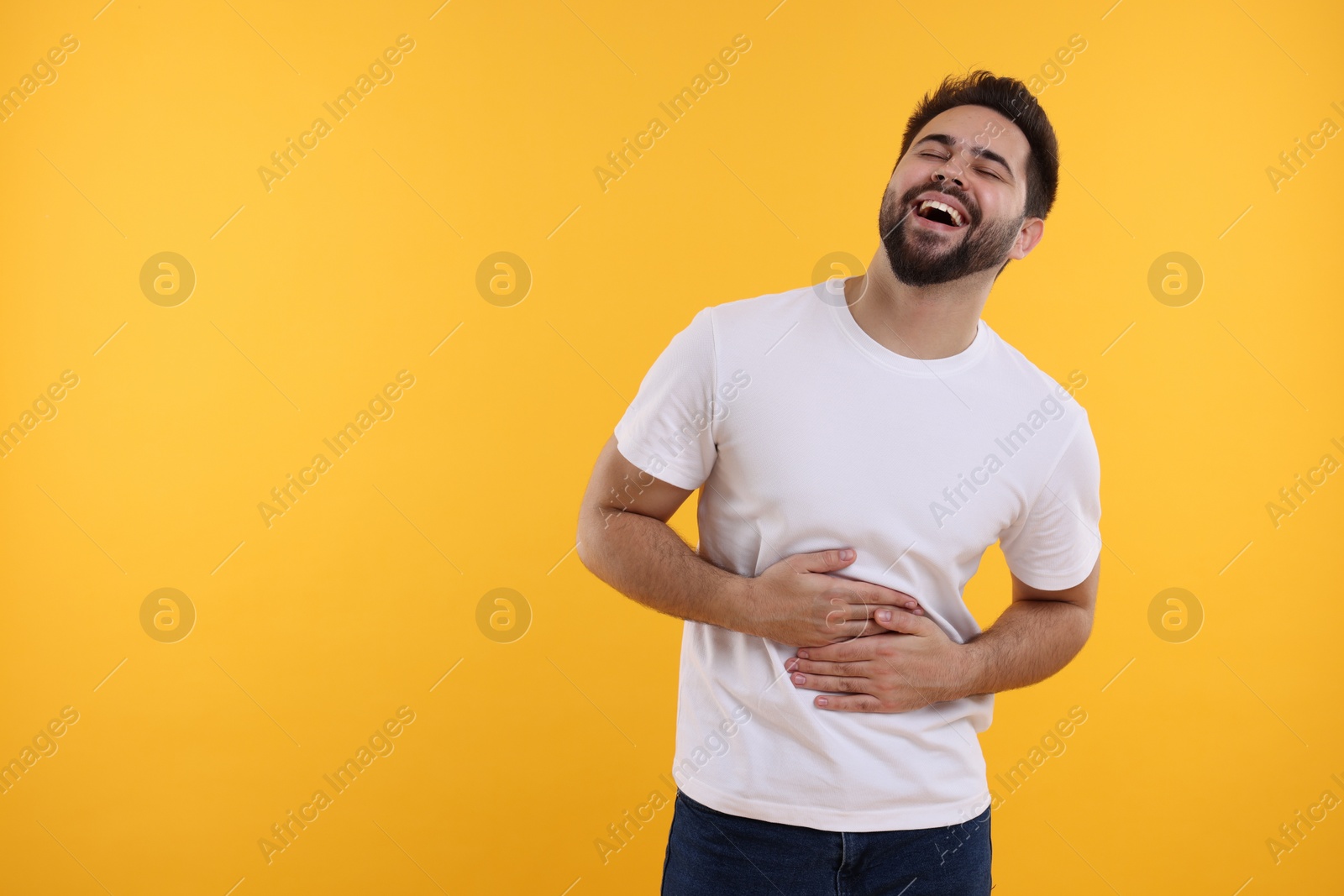 Photo of Handsome young man laughing on yellow background, space for text