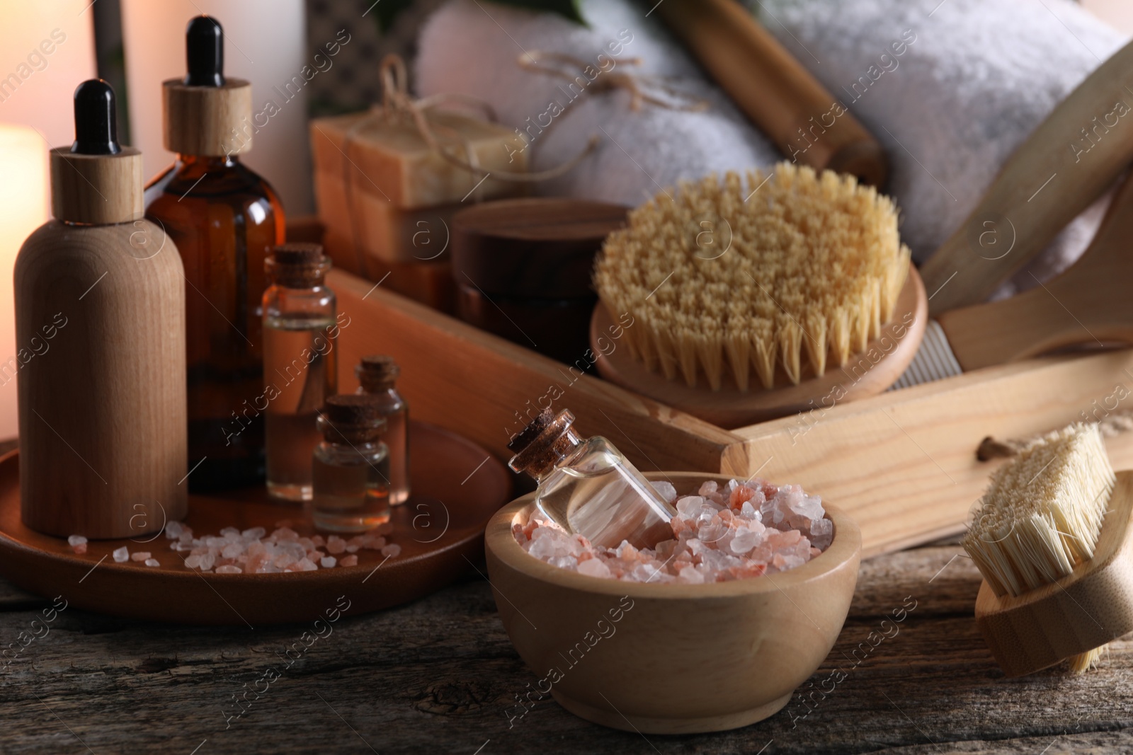 Photo of Spa composition. Bottles of cosmetic products, sea salt and brushes on wooden table