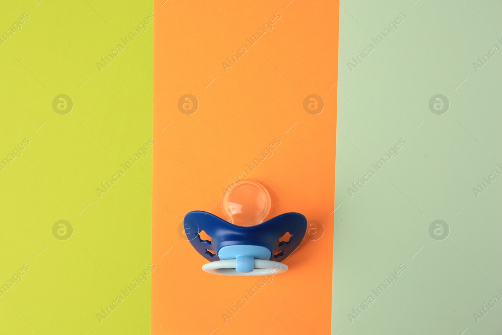 Photo of Baby pacifier on color background, top view