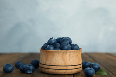 Fresh ripe blueberries in bowl on wooden table