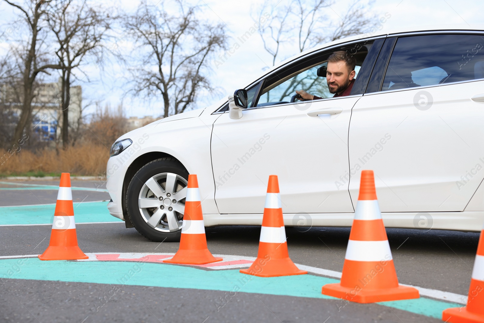 Photo of Young man in car on test track with traffic cones. Driving school