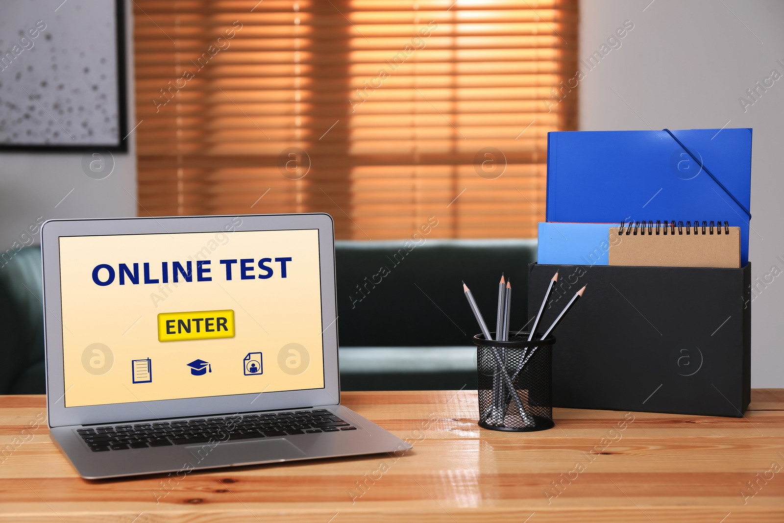 Photo of Laptop with online test and stationery on table in office