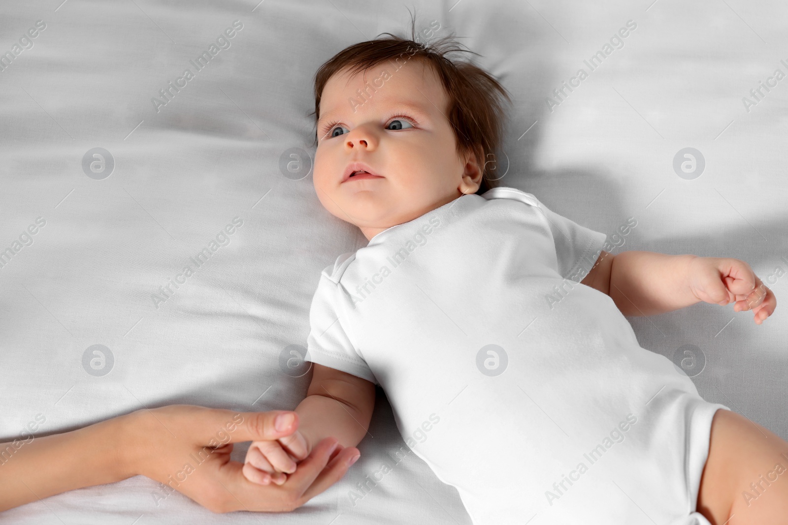 Photo of Mother holding hand of her little baby on bed, closeup