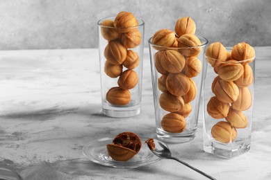 Photo of Tasty walnut shaped cookies served in glasses for welcoming guests on light grey table, space for text. Homemade pastry with caramelized condensed milk filling