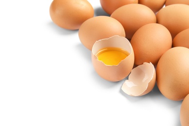 Cracked and whole chicken eggs on white background