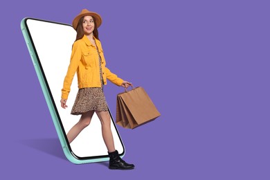 Online shopping. Happy woman with paper bags walking out from smartphone on dark violet background, space for text