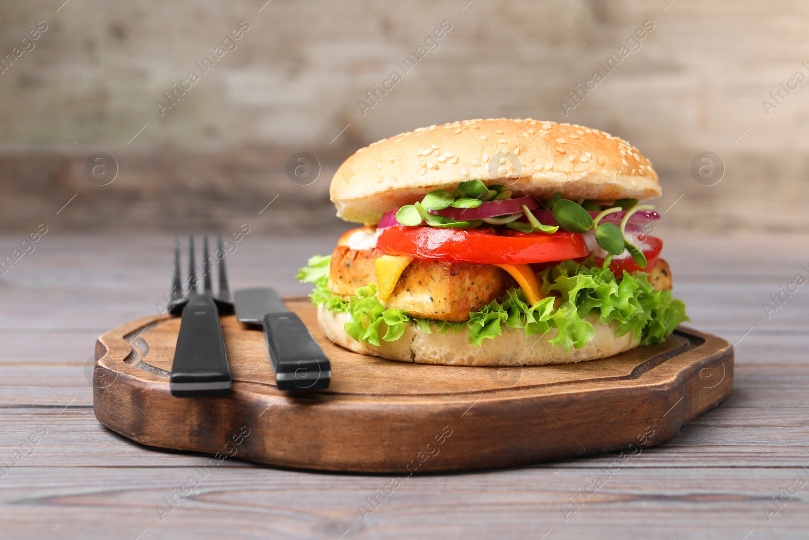 Photo of Delicious burger with tofu and fresh vegetables served on grey wooden table