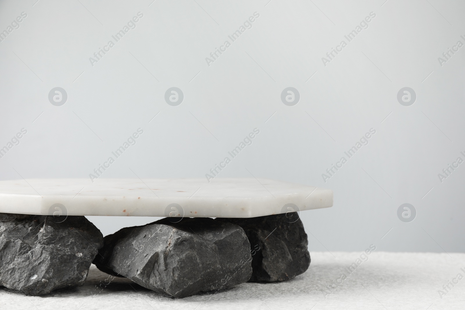 Photo of Presentation for product. Marble podium and stones on grey background. Space for text