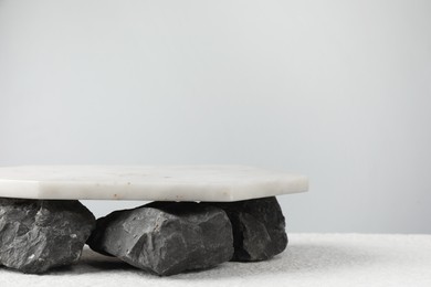 Photo of Presentation for product. Marble podium and stones on grey background. Space for text