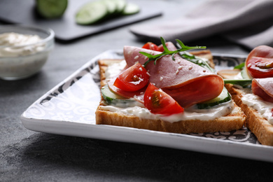 Photo of Tasty sandwiches with ham served on grey table, closeup