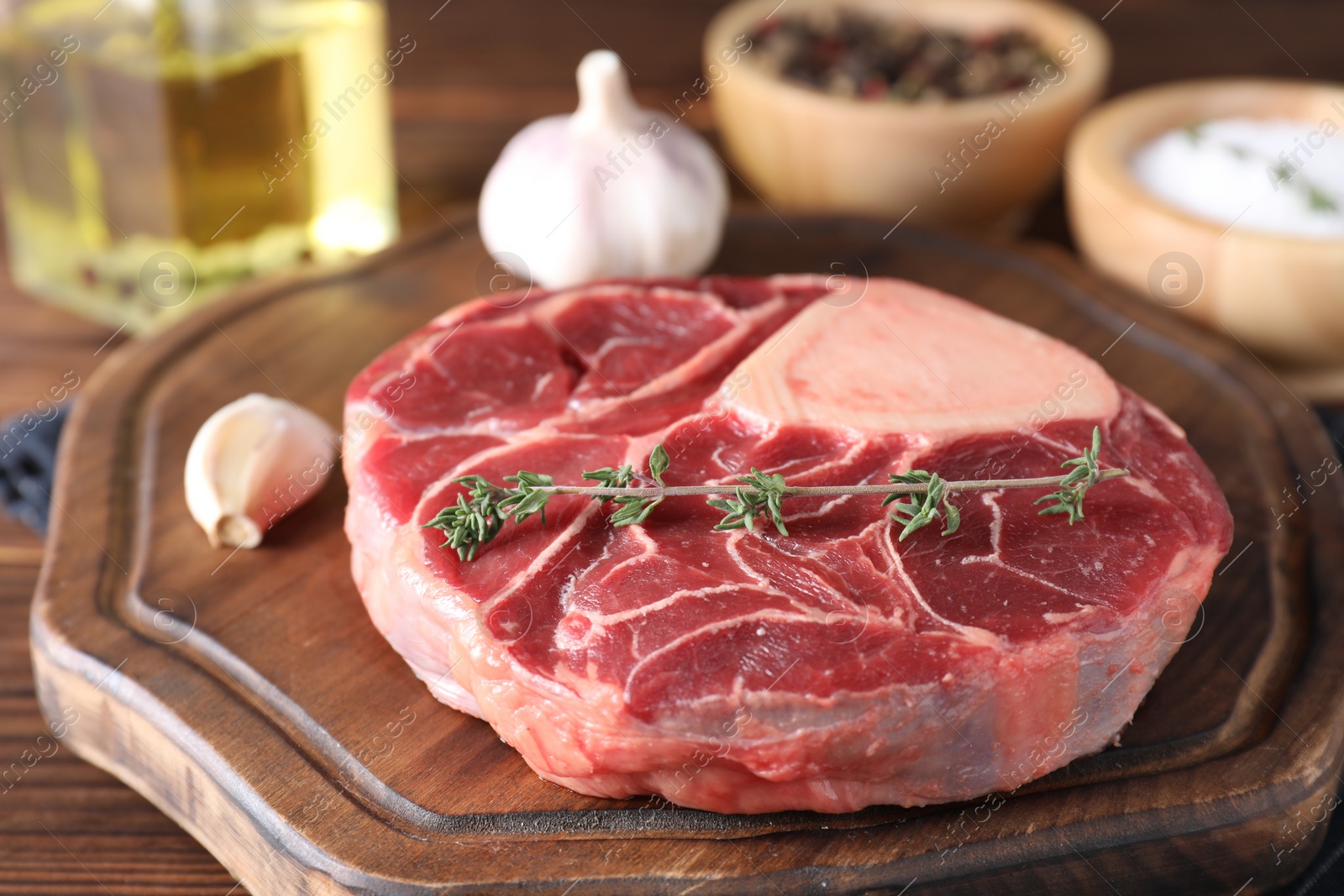 Photo of Piece of raw beef meat and thyme on wooden table, closeup