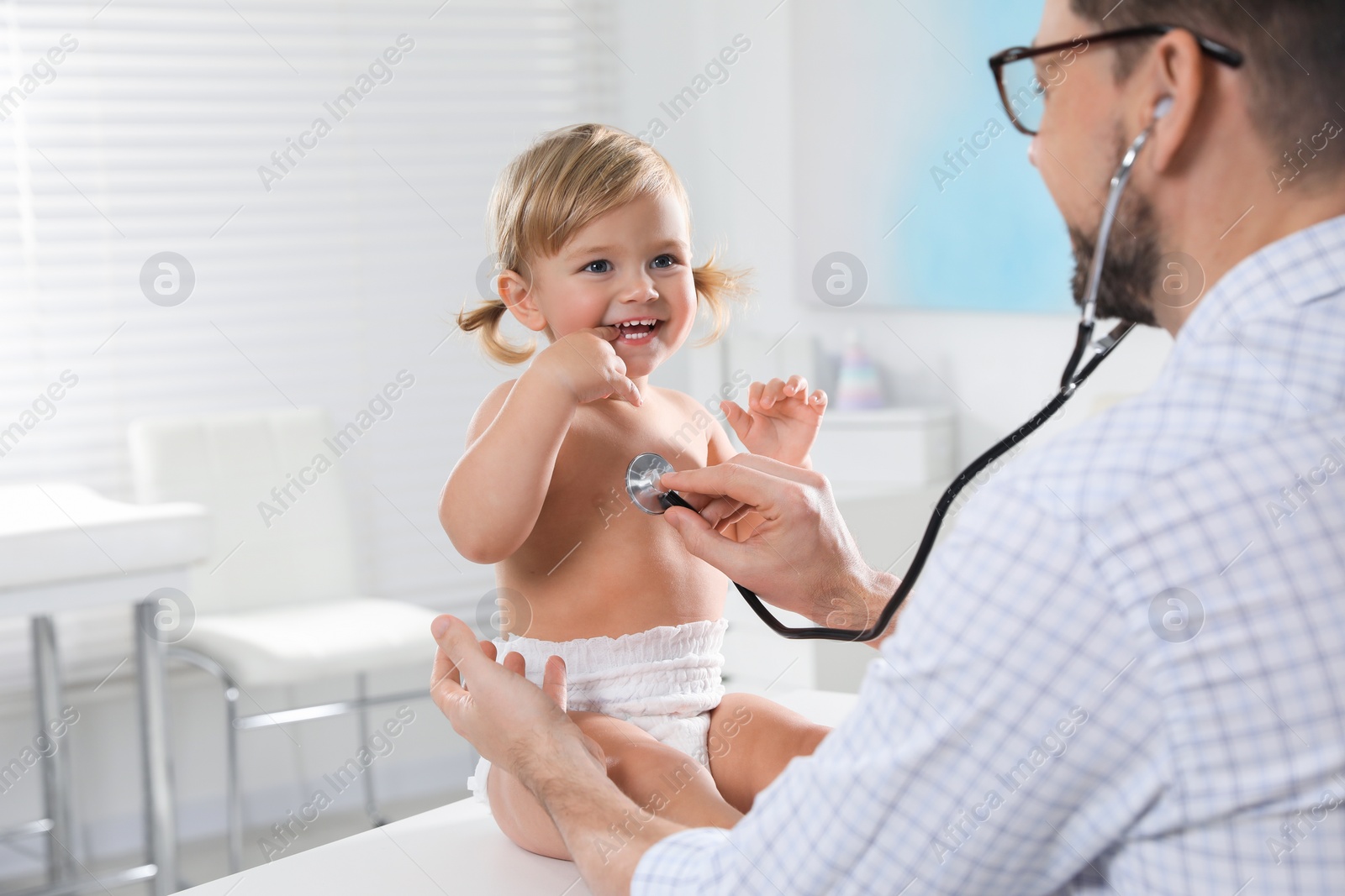 Photo of Pediatrician examining baby with stethoscope in clinic