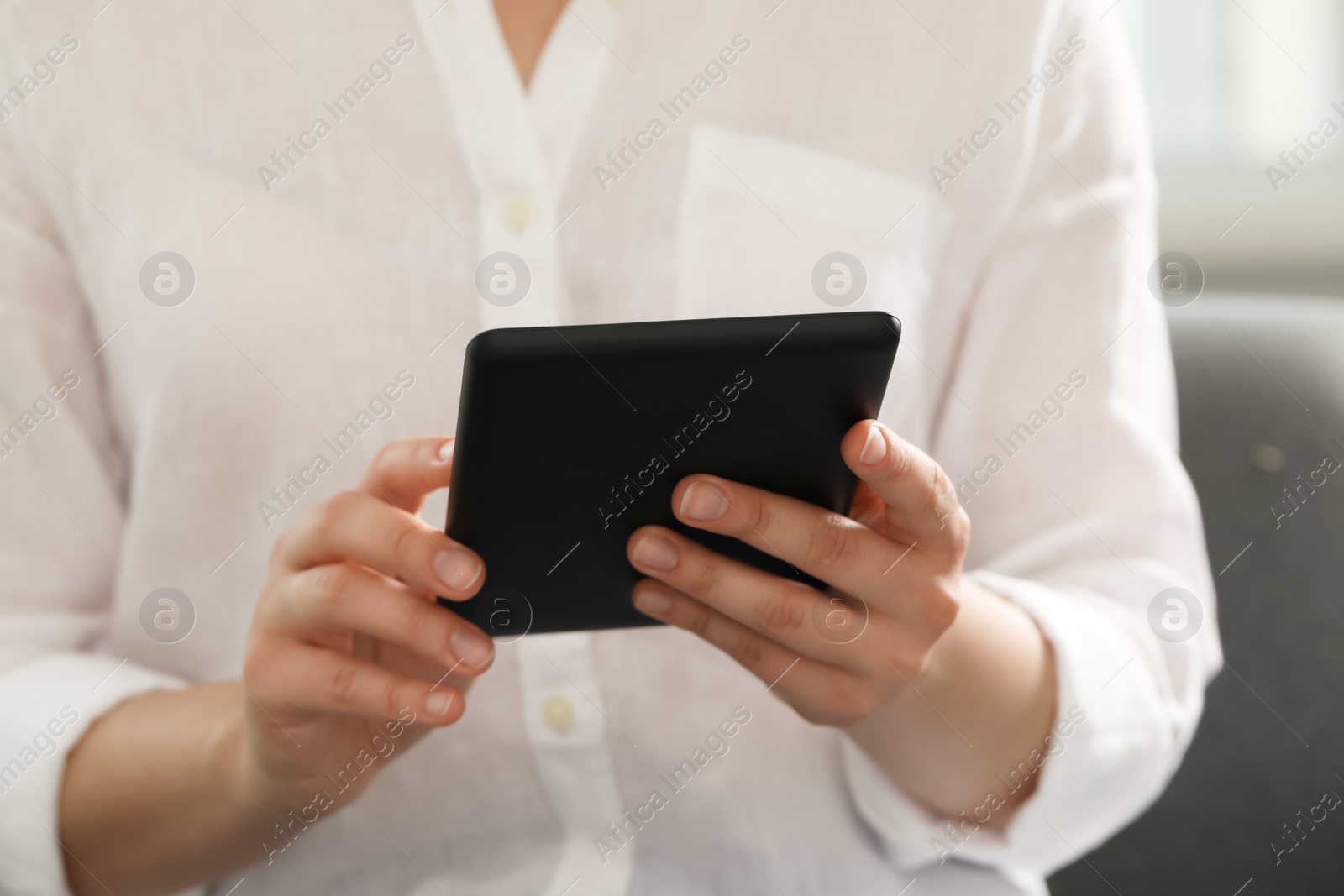 Photo of Young woman using e-book reader at home, closeup