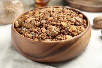Photo of Fresh tasty traditional kutia in wooden bowl on light towel, closeup