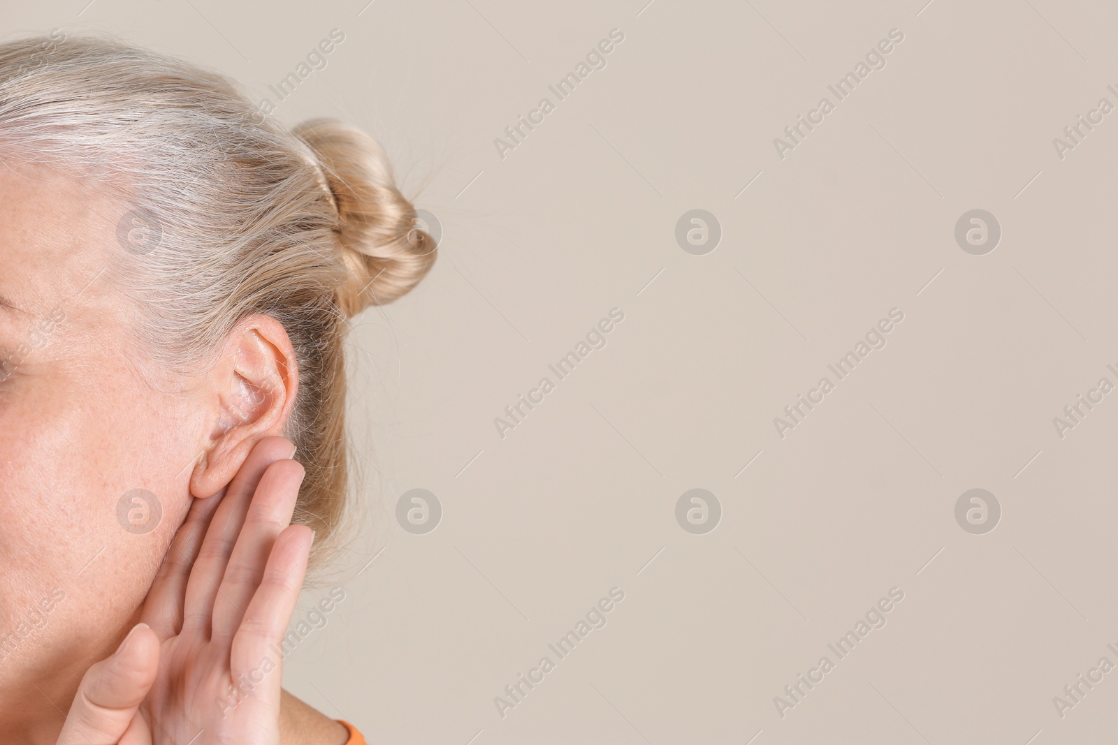 Photo of Mature woman with hearing problem on light background, closeup. Space for text