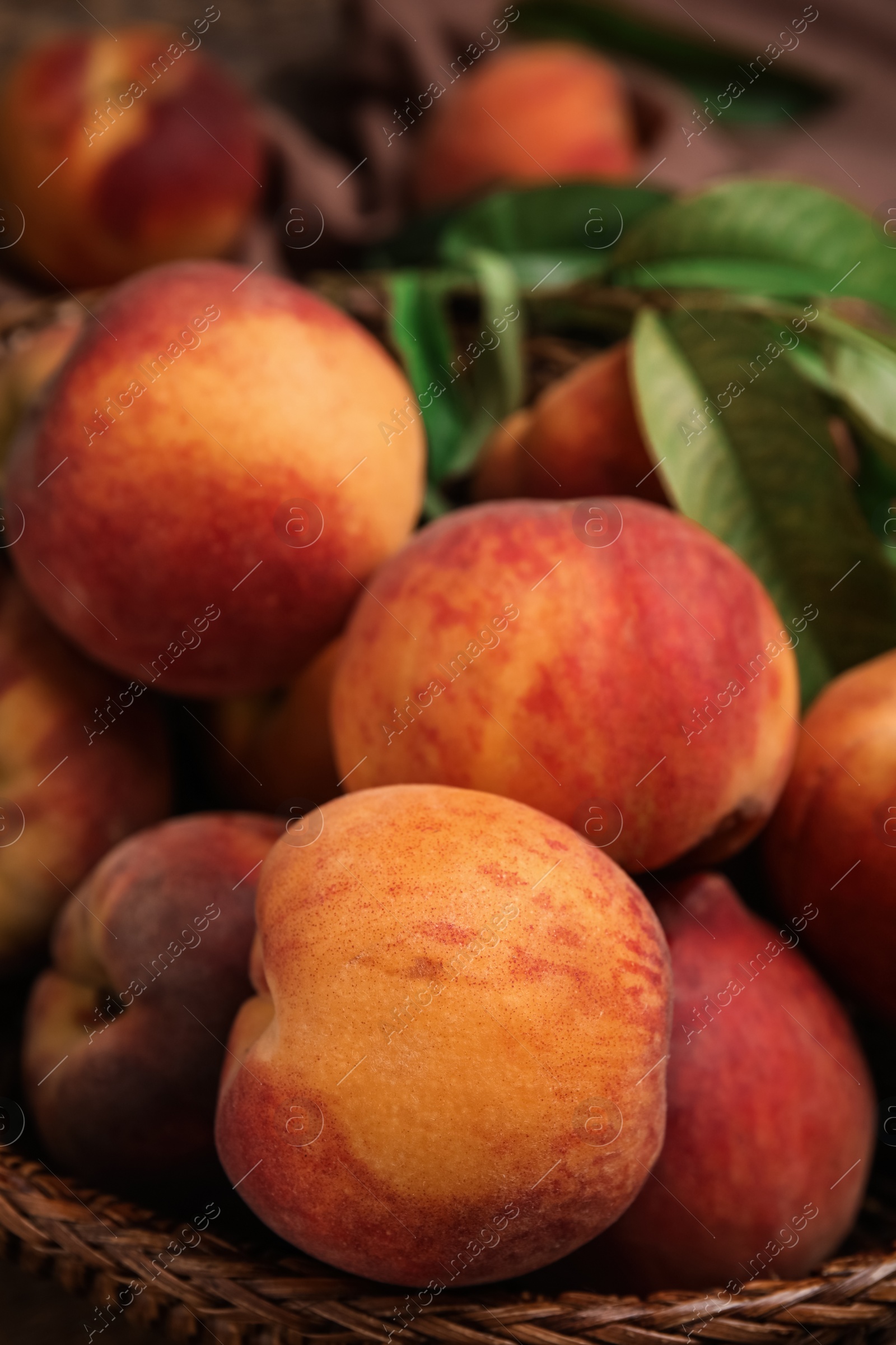 Photo of Fresh ripe juicy peaches in basket, closeup