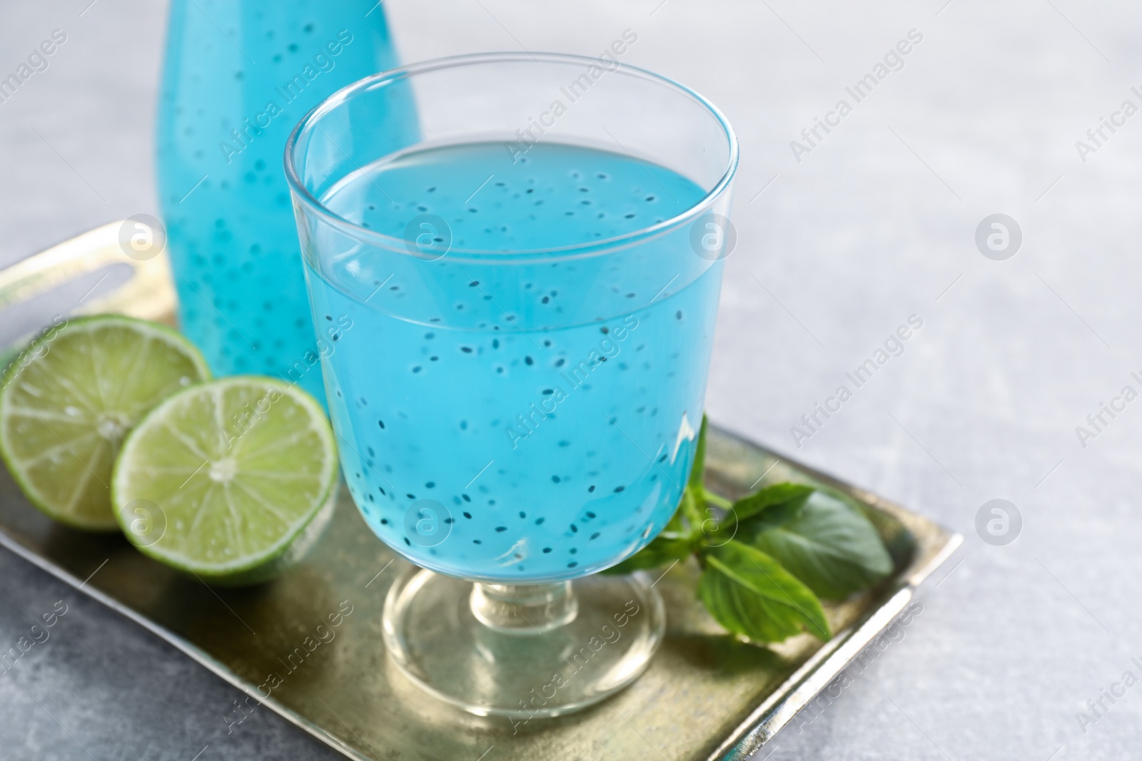 Photo of Tasty light blue drink with basil seeds on grey table