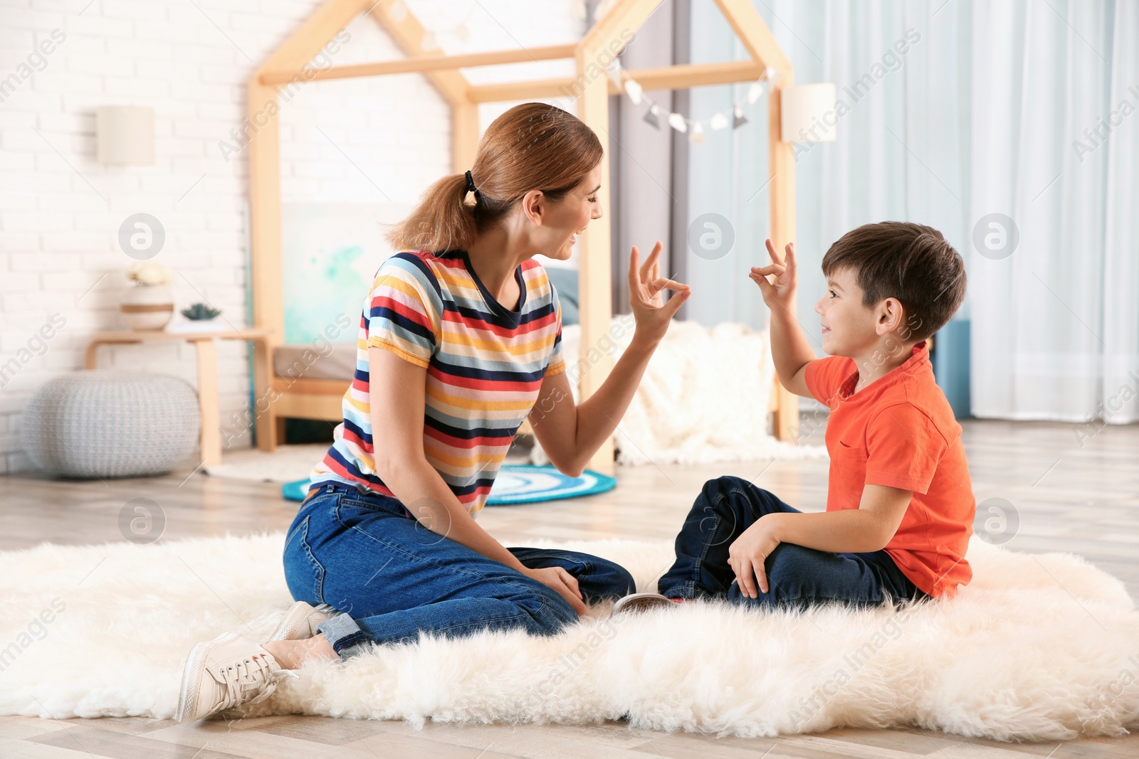 Photo of Hearing impaired mother and her child talking with help of sign language indoors