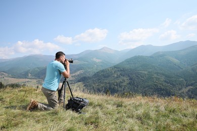 Professional photographer taking picture with modern camera in mountains. Space for text