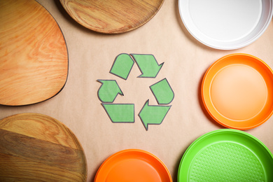 Photo of Recycling symbol, plastic and wooden plates on beige background, flat lay