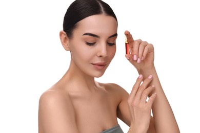 Beautiful young woman holding skincare ampoule on white background