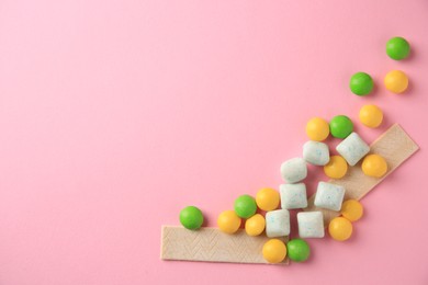 Photo of Different tasty chewing gums on pink background, flat lay. Space for text