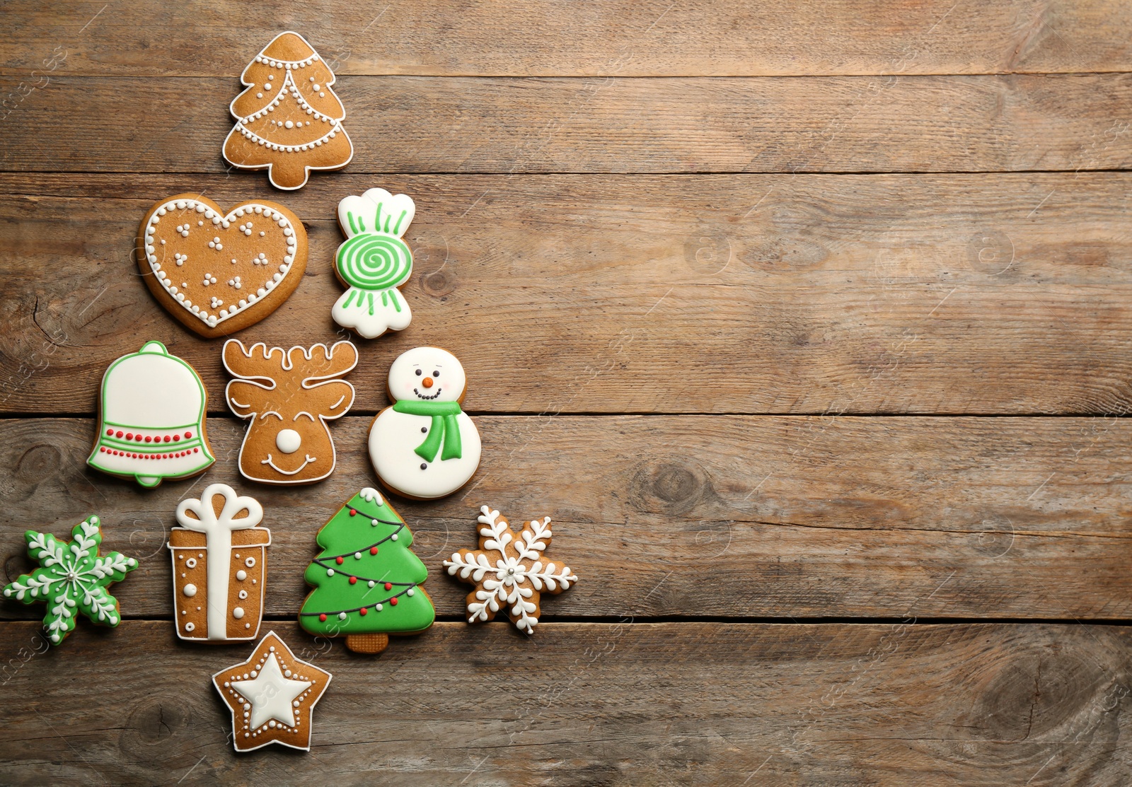 Photo of Christmas tree shape made of delicious gingerbread cookies on wooden table, flat lay. Space for text