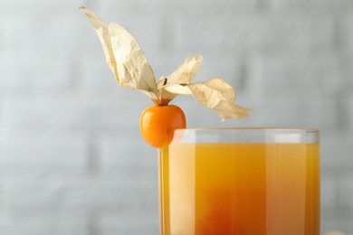 Photo of Delicious cocktail decorated with physalis fruit on blurred background, closeup