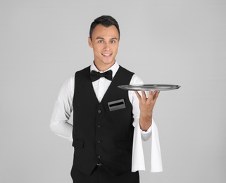Waiter holding metal tray on grey background