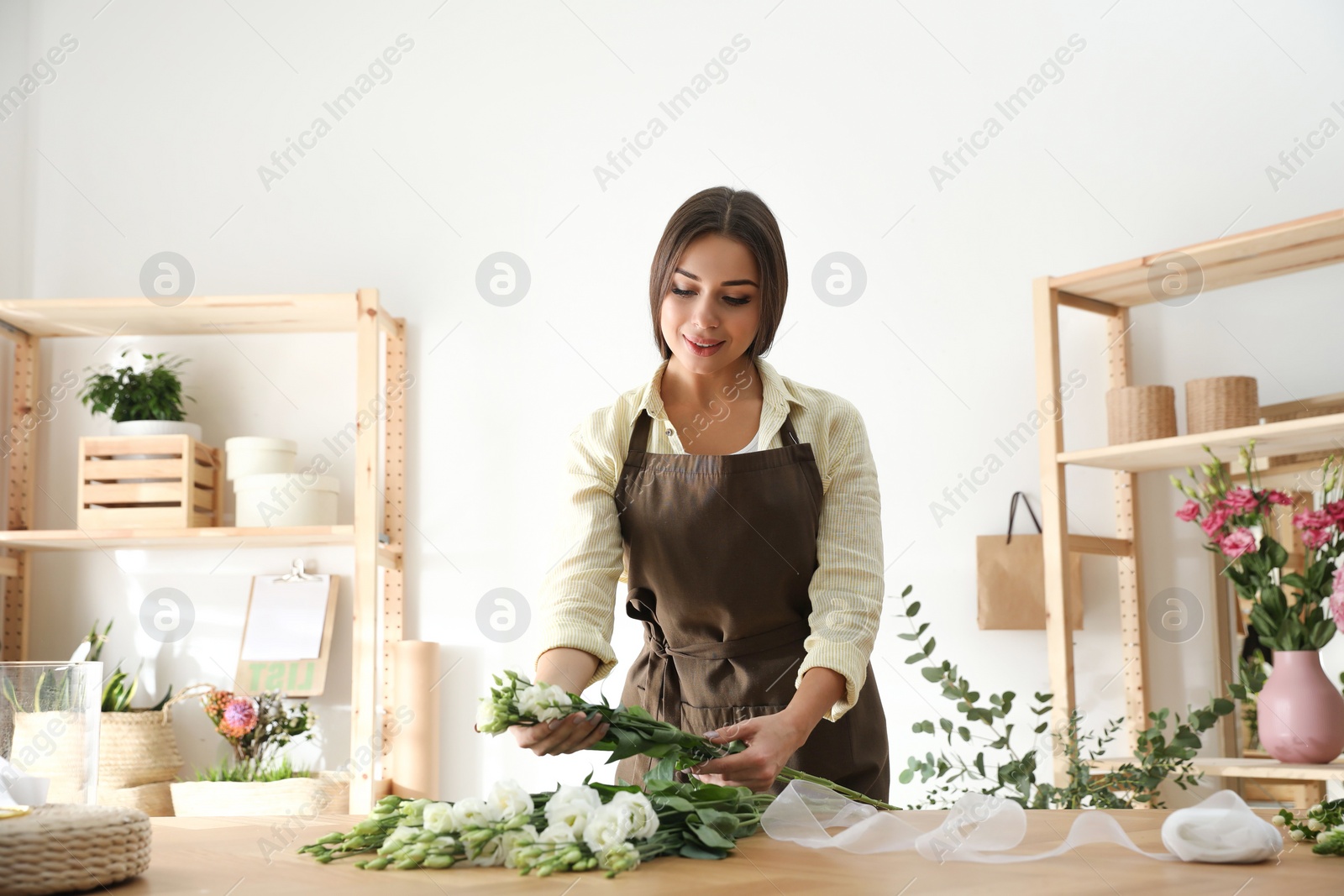 Photo of Florist making beautiful bouquet at table in workshop